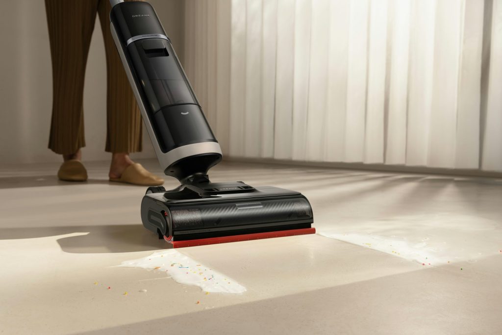 A person using a cordless vacuum cleaner on a floor.